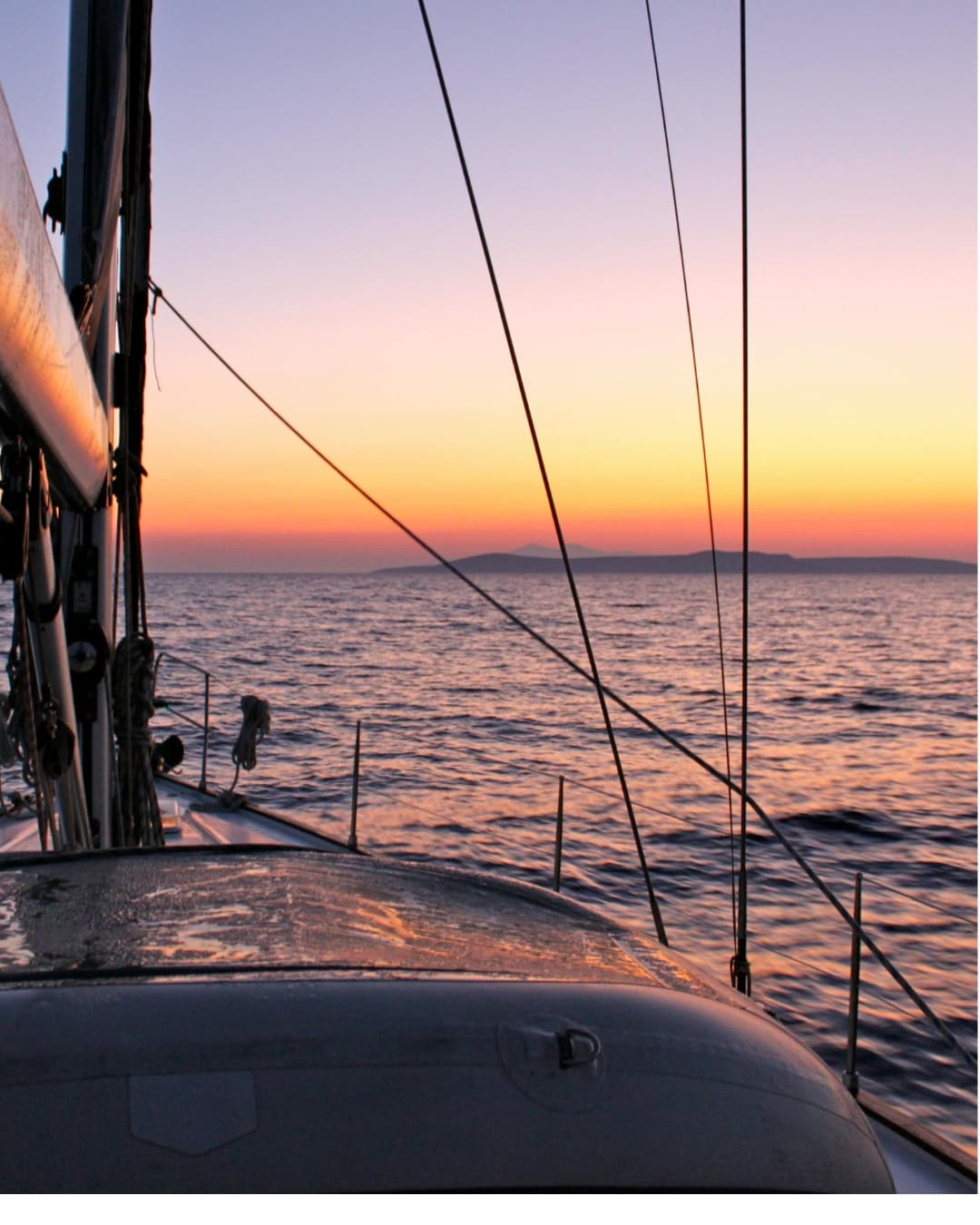 Sailing boat in open sea at sunset.